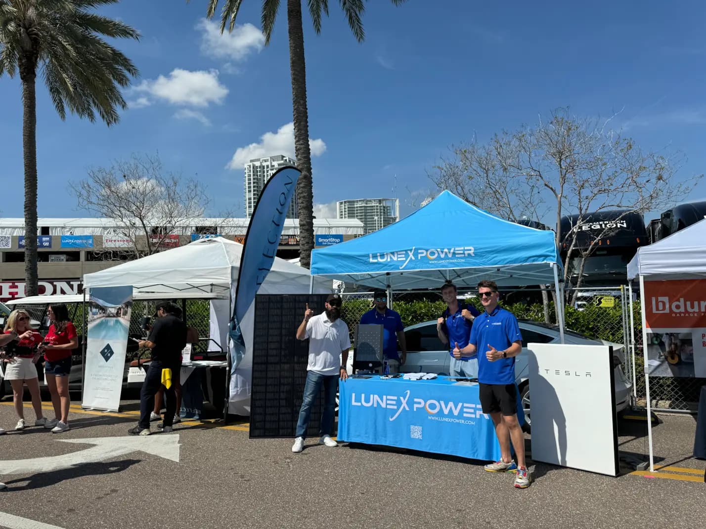 Lunex Power team at an outdoor event booth with branded tents and solar equipment.