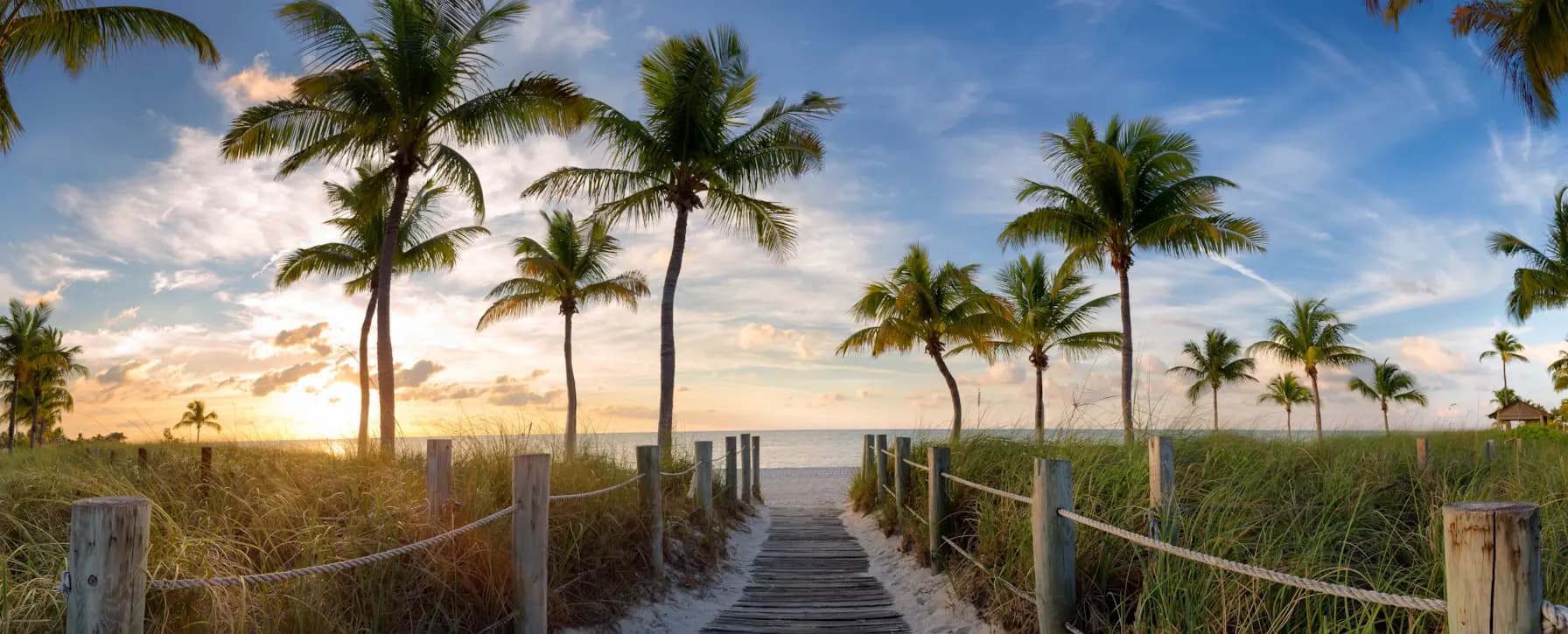 Palm-lined beach boardwalk in Key West, Florida at sunrise.