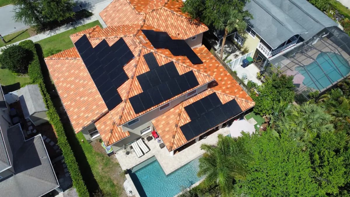 Aerial view of Lunex rooftop solar panels on a Florida home with a red tile roof and backyard pool.