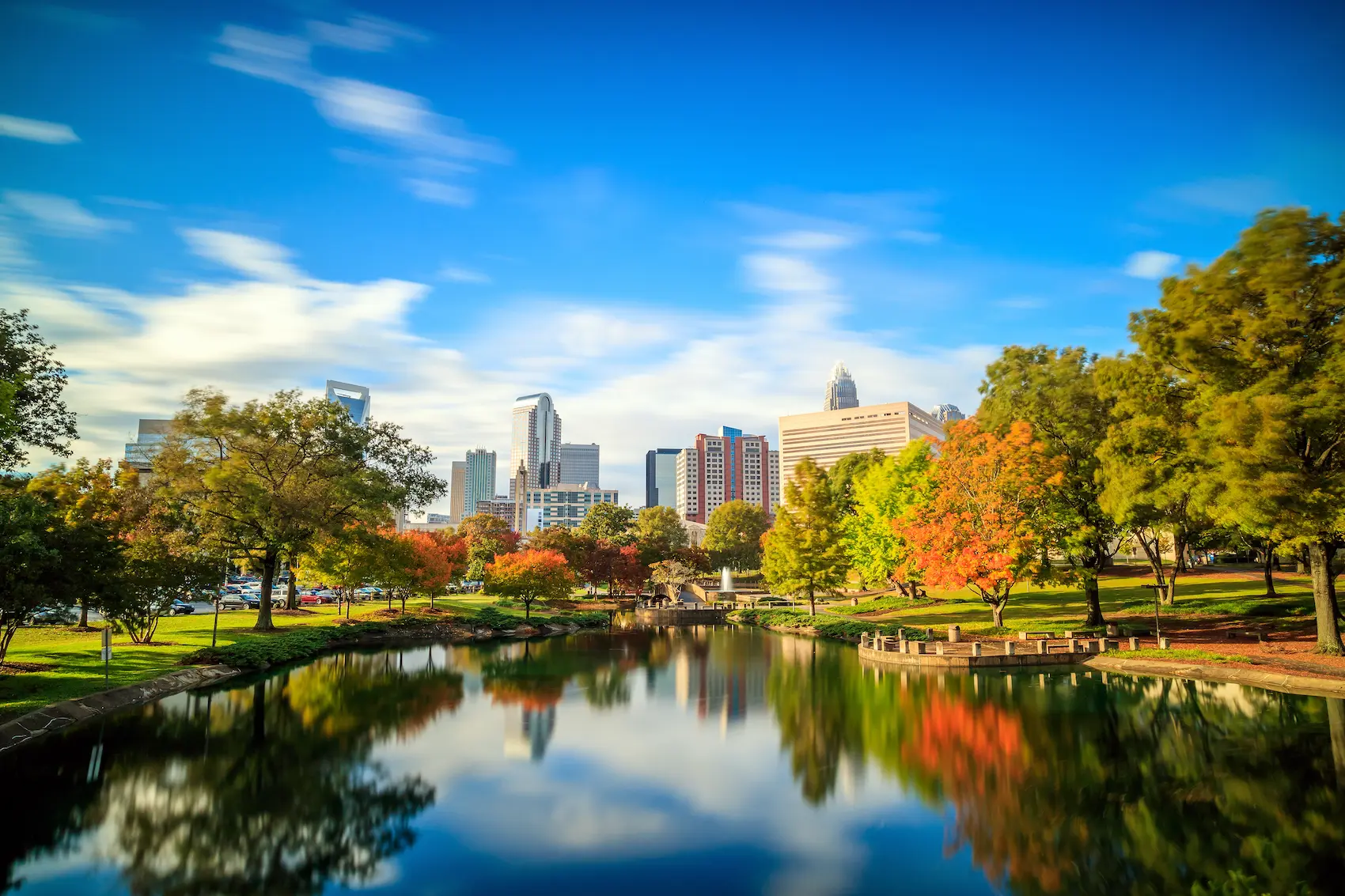 Charlotte, North Carolina skyline reflected in a park lake under a clear sky.