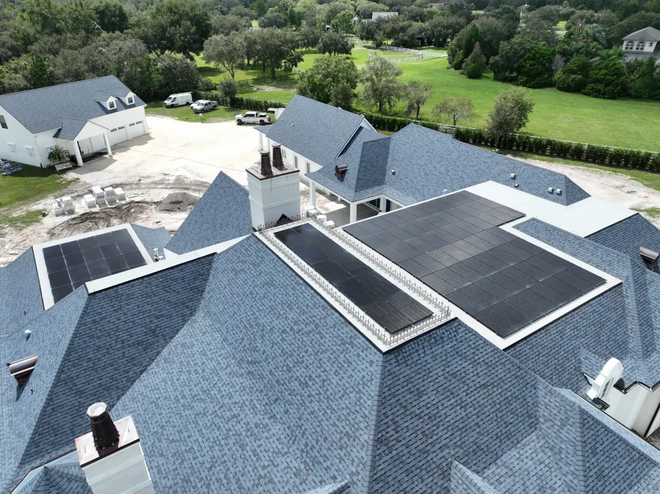 Large rooftop solar array installed on a blue shingle home surrounded by trees.