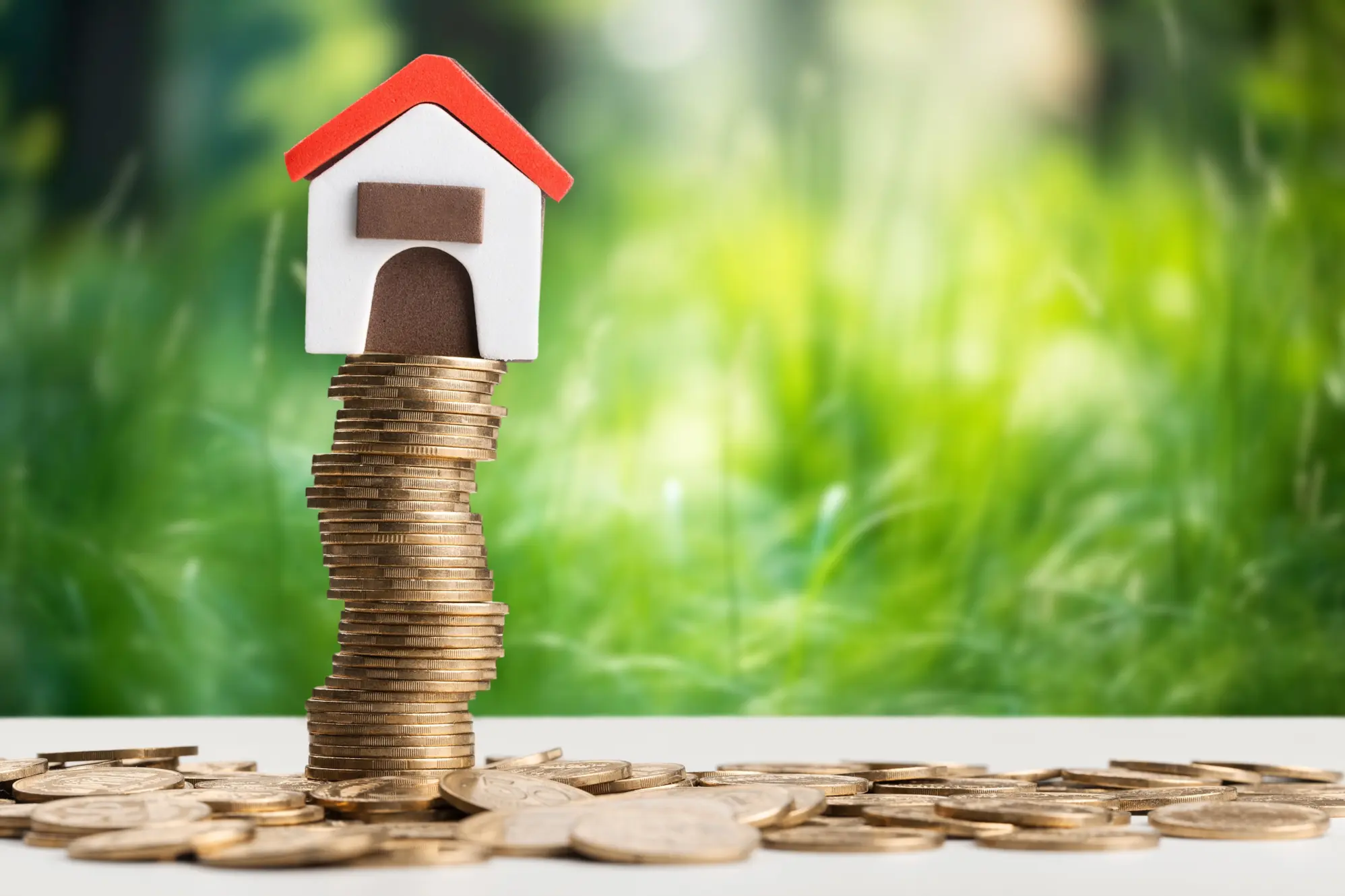 Small house model sitting on a tall stack of coins, symbolizing solar incentives and home energy savings.