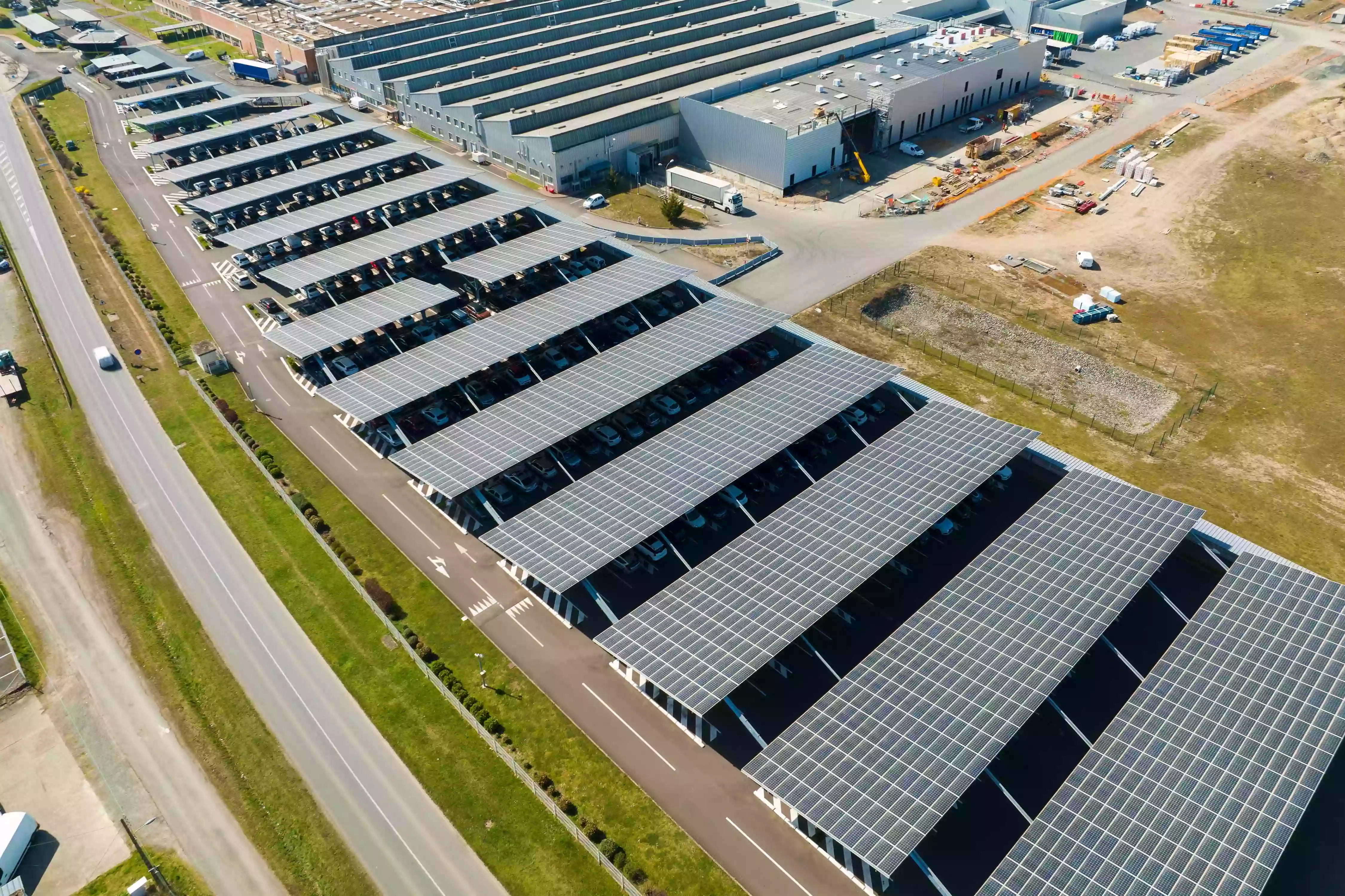 Aerial view of solar carport canopies shading vehicles in a commercial parking lot.