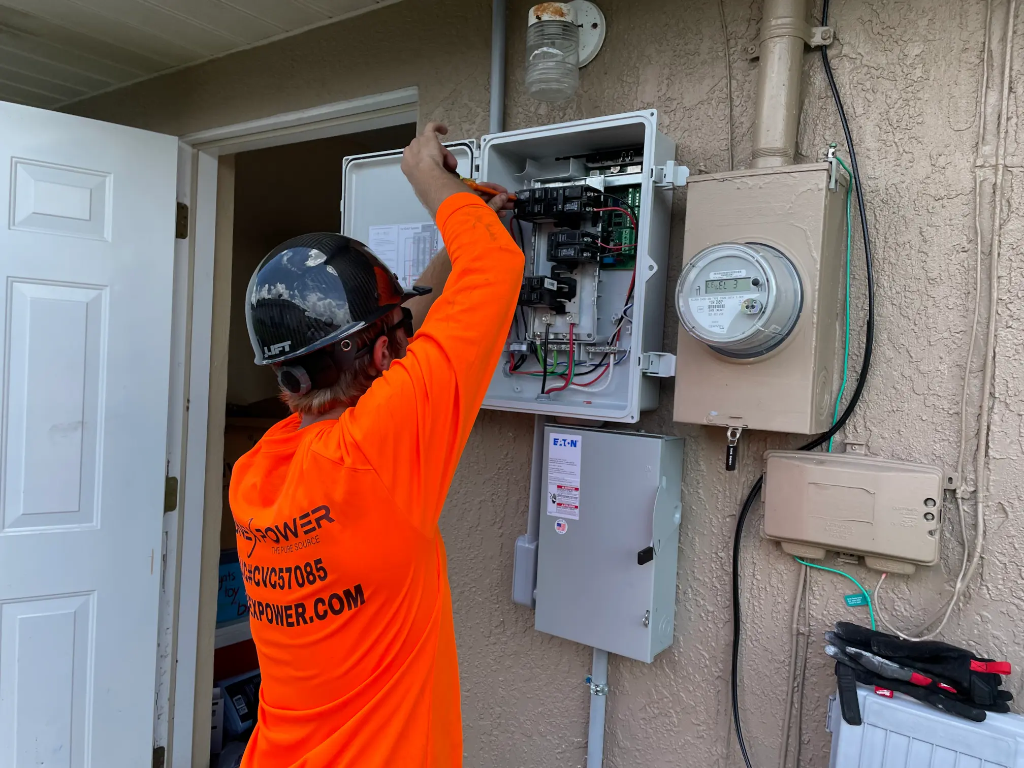 Lunex Power technician servicing an exterior residential electrical panel.