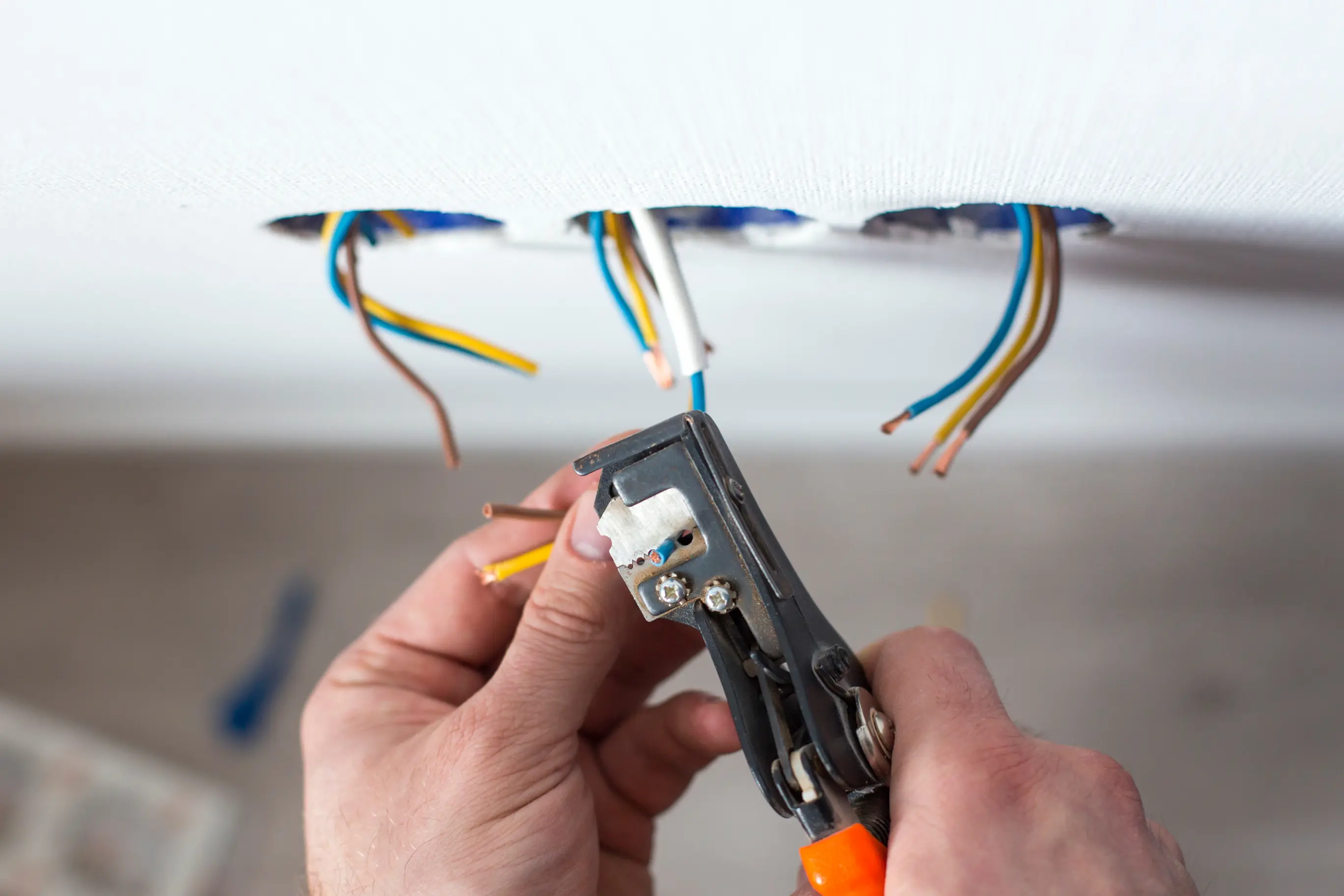 Electrician stripping insulation from electrical wires during a residential wiring project.