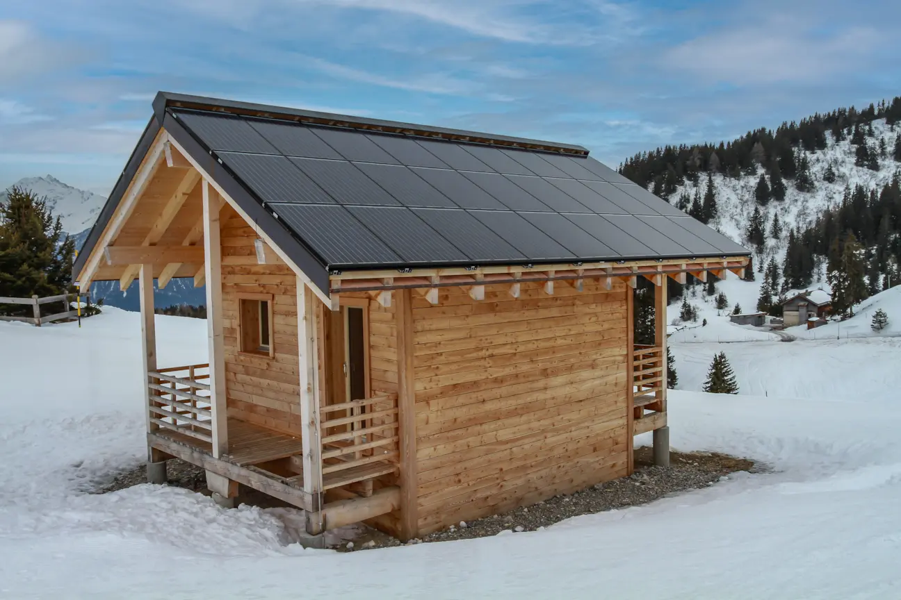 Remote wooden cabin in snowy mountains powered by rooftop solar panels.