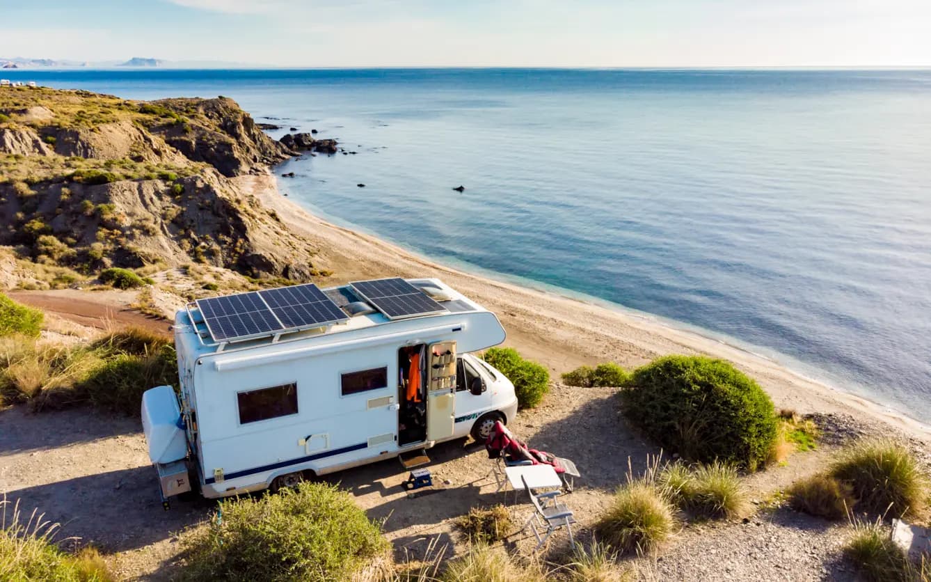 Off-grid RV parked at a beach campsite with solar panels on the roof.