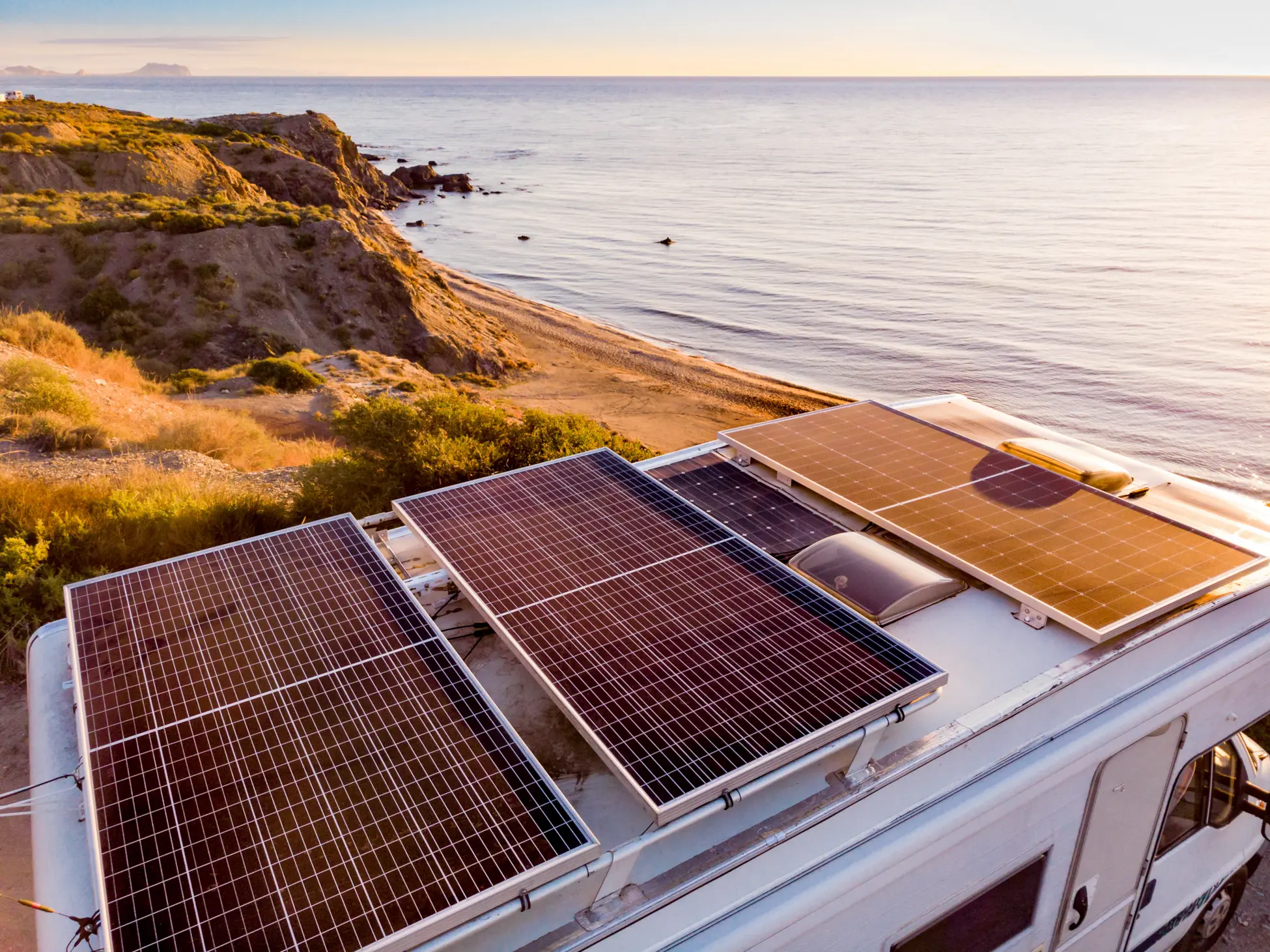 Rooftop solar panels on an off-grid RV parked at a coastal campsite, generating renewable power.