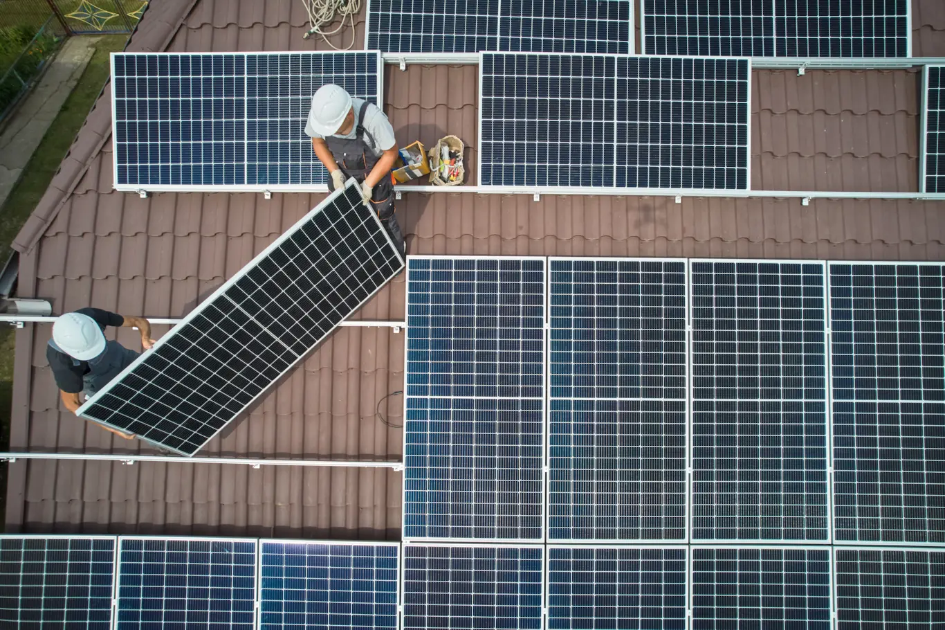 Solar installers adding panels to a residential rooftop solar array during a system expansion.