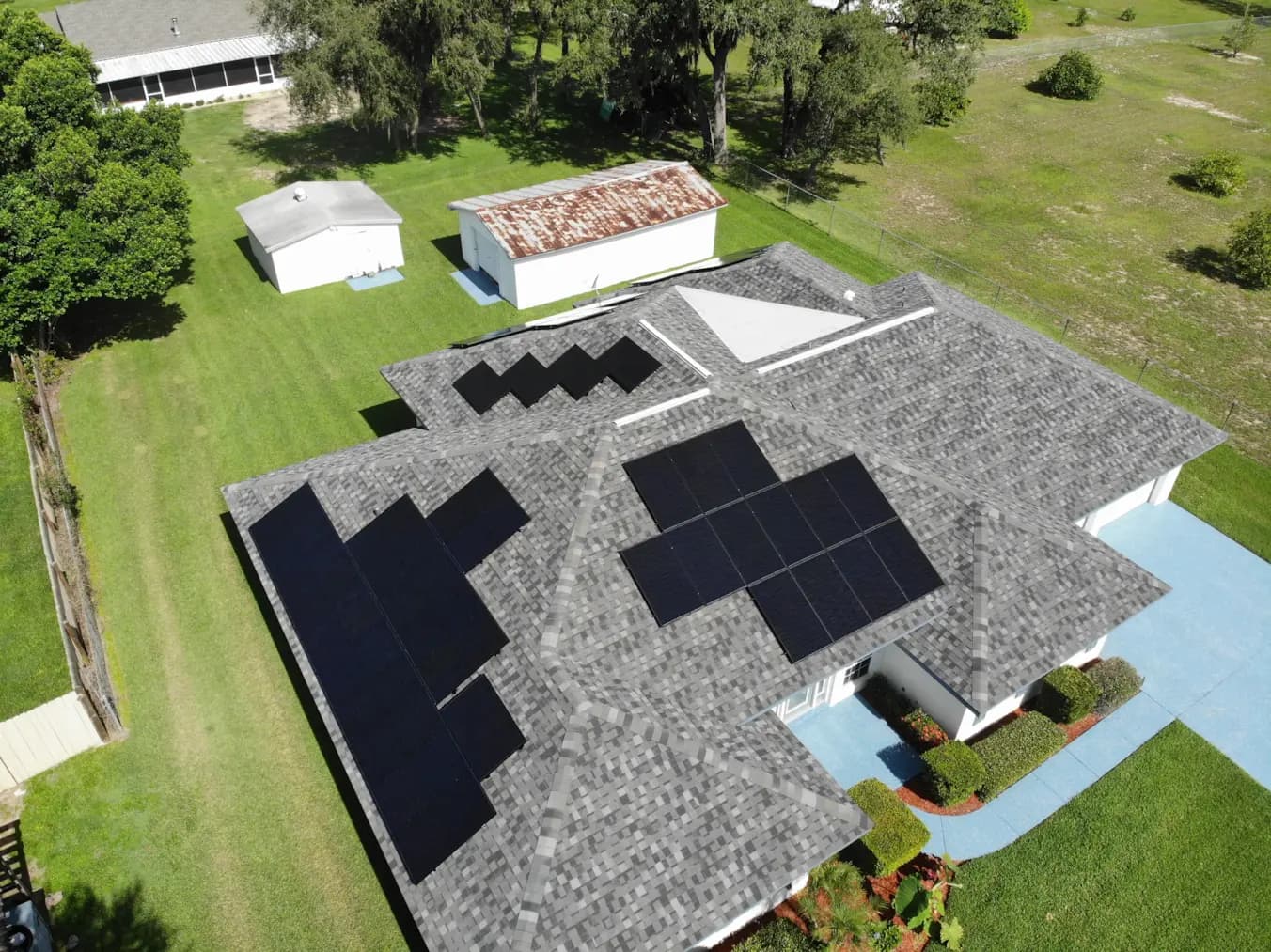 Large Lunex solar array on a grey shingle roof with a curved blue driveway.