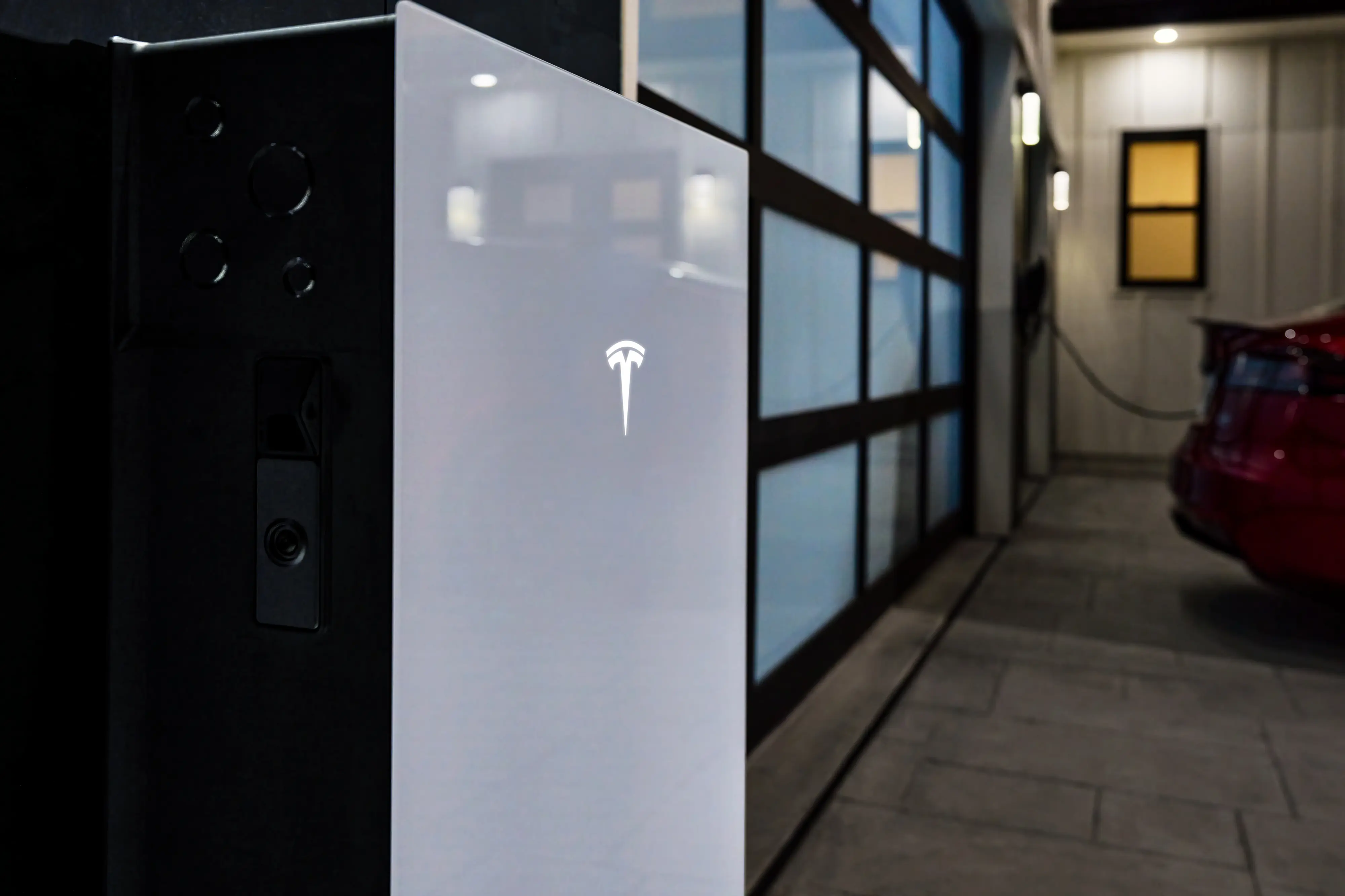 Tesla Powerwall home battery installed in a modern garage next to an electric vehicle.