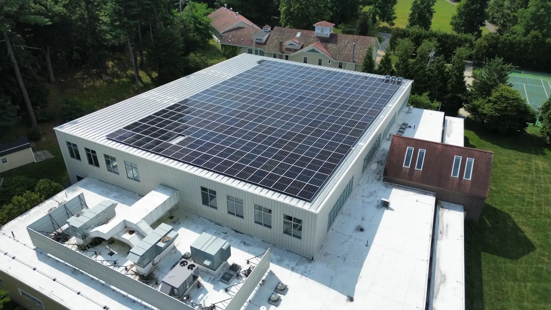 Aerial view of a rooftop commercial solar panel installation by Lunex Power on a school building